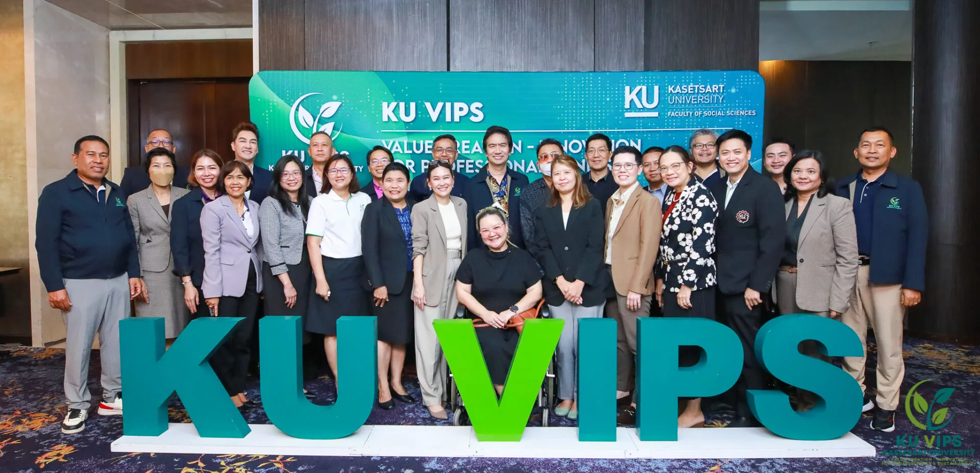 ภาพถ่ายกลุ่มของคณาจารย์และผู้เข้าร่วมงาน KU VIPS จากมหาวิทยาลัยเกษตรศาสตร์ คณะสังคมศาสตร์ ยืนเรียงหน้ากระดานพร้อมรอยยิ้มอยู่ด้านหลังอักษรสามมิติขนาดใหญ่ ‘KU VIPS’ สีเขียวและฟ้า มีพื้นหลังเป็นป้ายแสดงชื่อโครงการและโลโก้ของมหาวิทยาลัย